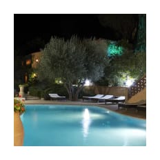 Athénopolis pool illuminated at night beside an olive tree